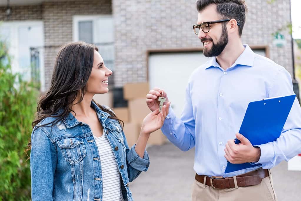Realtor handing keys to a young woman at her new house